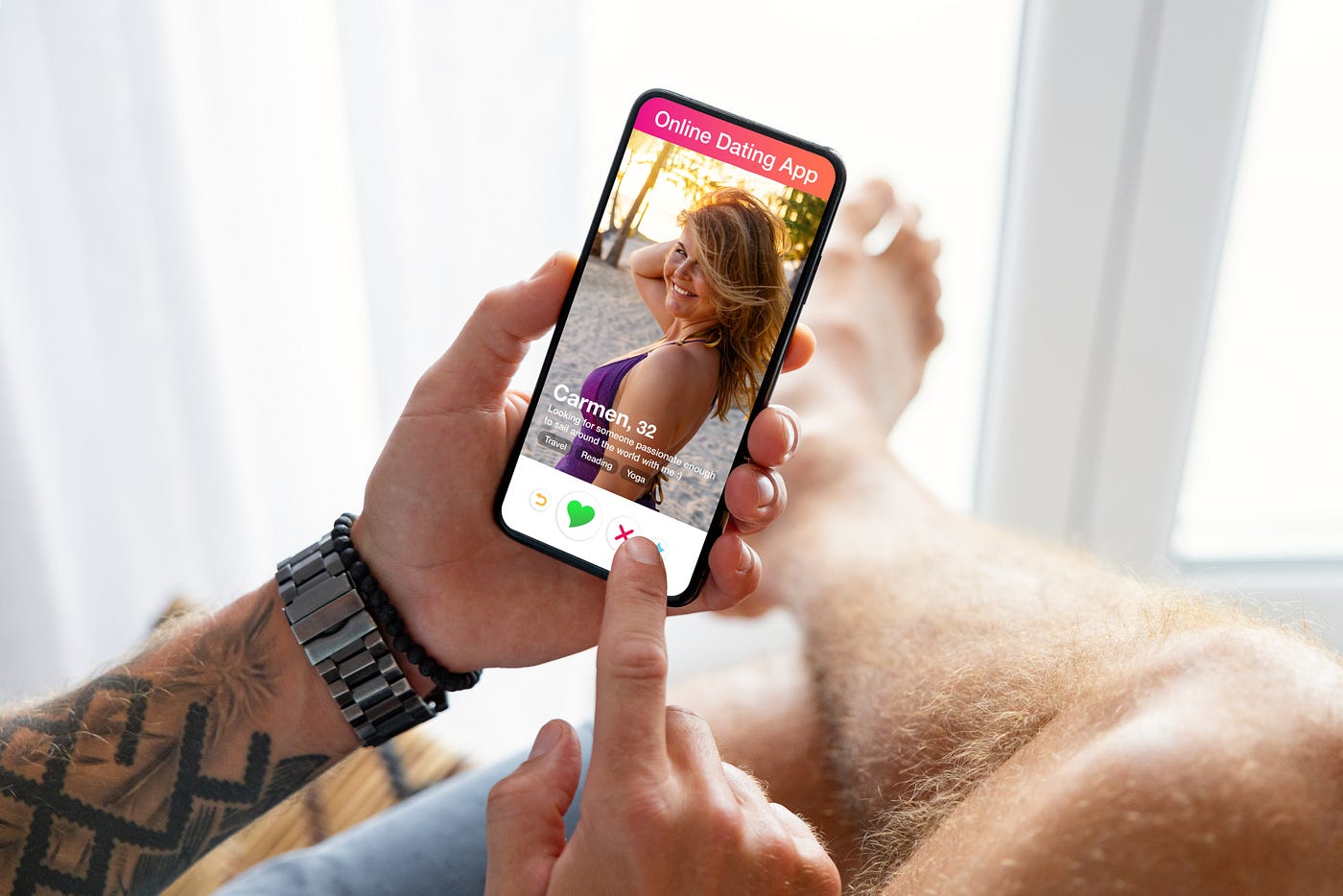A man's tattooed arm and hand holding a smartphone with an online dating app