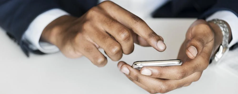 A person in a suit with a watch, holding a smartphone